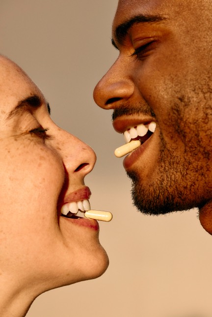 Two people smiling with fertility pills in their mouths