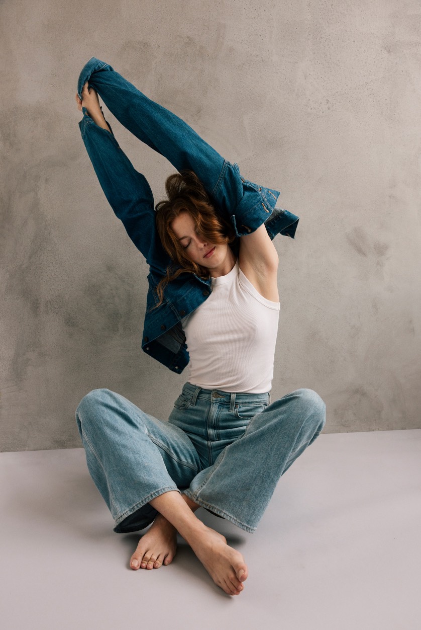 Woman stretching in studio with jean jacket on