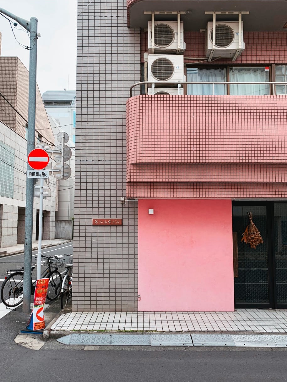 Tokyo Street with a pink and grey building with bikes down the street